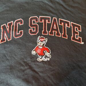 MV Sport brand Black NC State Tee. Adult MEDIUM. Sm tear at bottom.